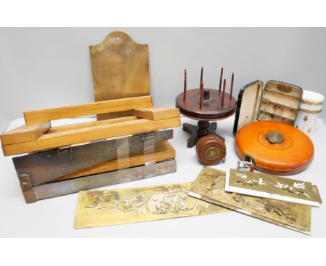 A collection of printing plates, two leather measuring tapes including one dated 1915, a wooden paper cutter, a wooden bobbin