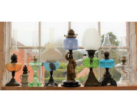 A collection of eight oil lamps to include a chamber oil lamp and flute, 33.5cm high, a figural example with blue mottled res