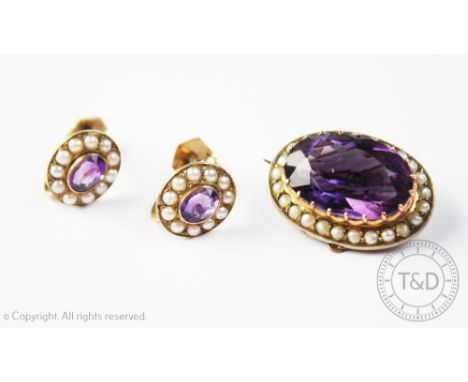 An amethyst and seed pearl set brooch and matched earrings, designed as a central oval, mixed cut amethyst within a surround 