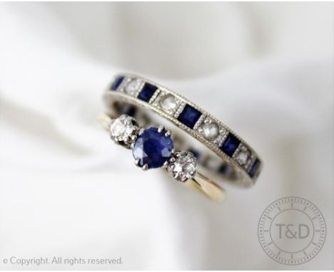 A sapphire and diamond three stone ring, all claw set in white metal to the tapering yellow metal shoulders and plain hoop st