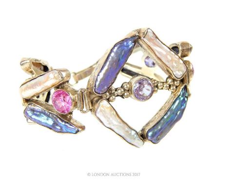 A stunning, handmade, sterling silver baroque pearl and coloured crystal bracelet composed of twelve, long, collet-set, dyed 