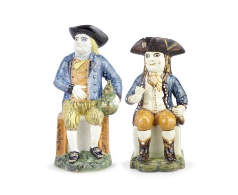 Two Portuguese 'Sailor' Toby jugs, circa 1800Modelled seated and holding a flask, one in creamware and wearing a blue jacket 