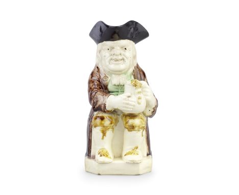 A creamware Toby jug, circa 1785Of traditional form, modelled seated and holding an overflowing foaming jug in both hands, we