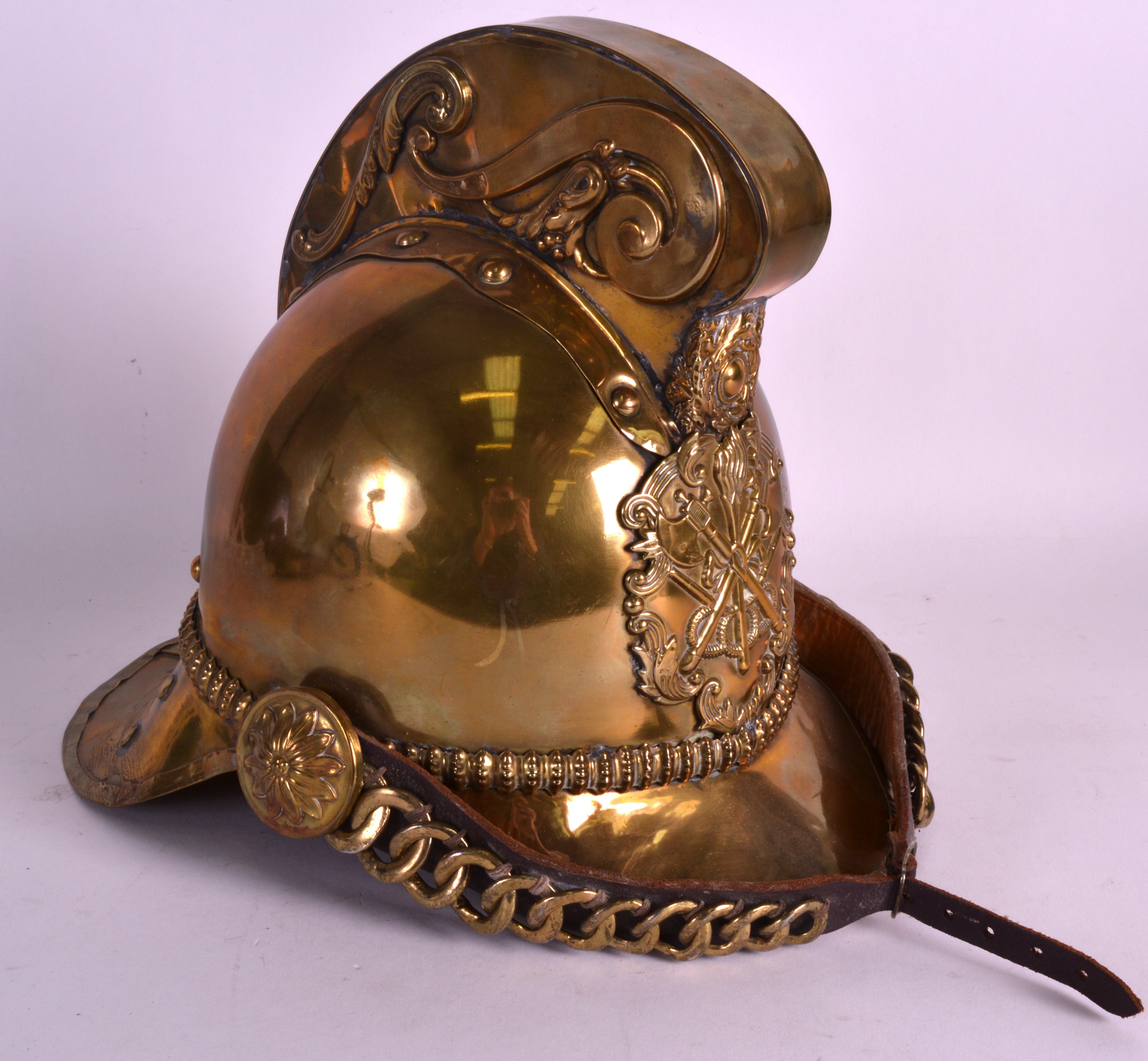 A LATE VICTORIAN BRASS FIREMANS HELMET with central panel decorated