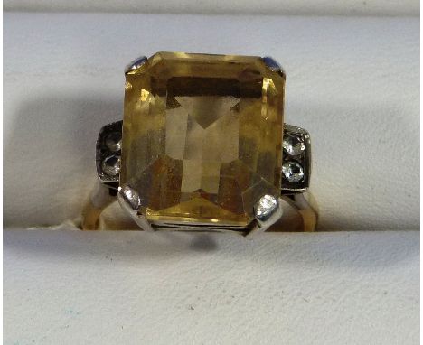 A large step cut citrine Ring, with two small diamond points on each shoulder, mounted in white and yellow metal. Size R.