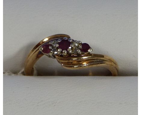 A small three stone ruby  Ring, set on the cross with two diamond points on each side of the central stone mounted in 9ct yel