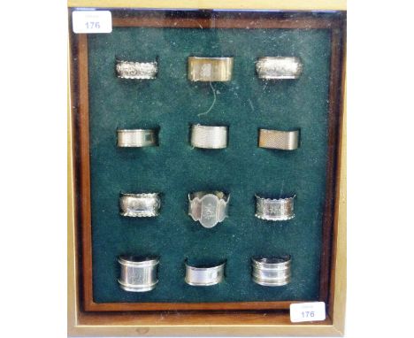 Silver Napkin Rings; a mounted and framed collection of twelve napkin rings (eleven silver and one silver-plated), various de