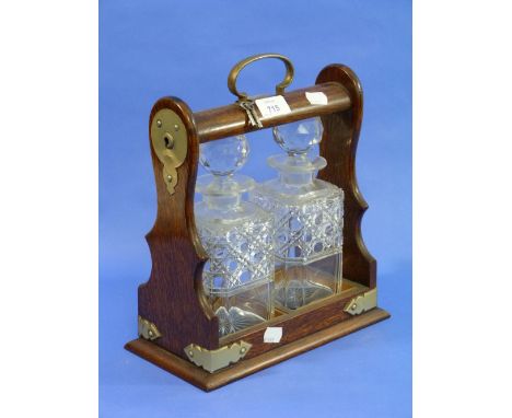 A mid 20thC oak and silver plate mounted two decanter Tantalus, with key.