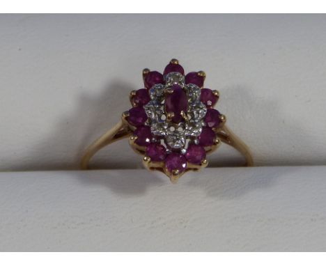 An oval cluster Ring, set with a central pale ruby surrounded by eight diamond points with outer surround of twelve pale rubi