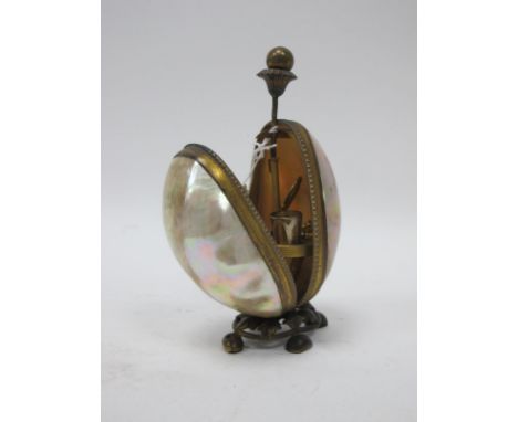 A Late XIX Century Sewing Stand, the egg shaped mother of pearl case with gilt metal mounts opening to reveal scissors, thimb