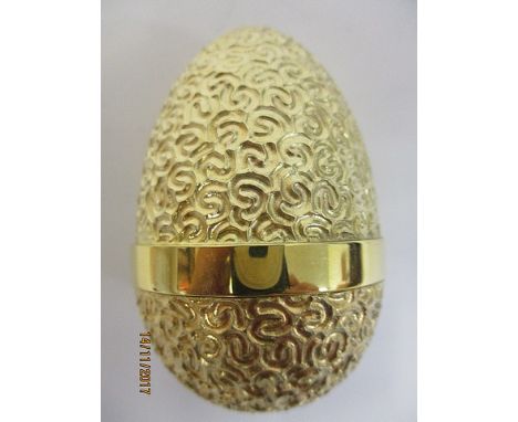 A silver, gilt surprise egg by Stuart Devlin, London 1980 having a textured, scrolled decoration, revealing a jack in a box w