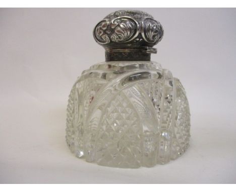 A late Victorian clear glass inkwell with a silver, hinged cap by Mappin Brothers, London 1900, embossed and chased with foli