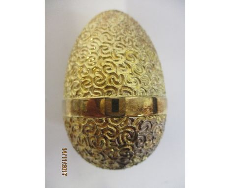 A silver gilt surprise egg by Stuart Devlin, London 1980 having a textured, scrolled decoration revealing a jack in a box wit