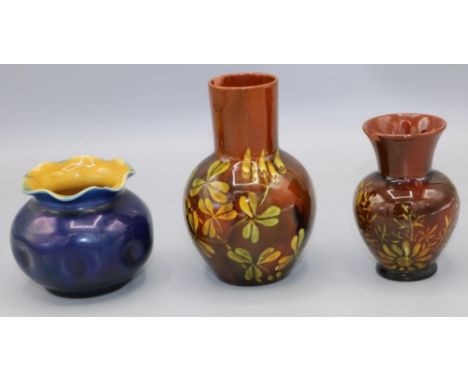 Two Linthorpe pottery brown glazed vases, decorated with flowers, and a blue glazed globular vase body and angular tapering n