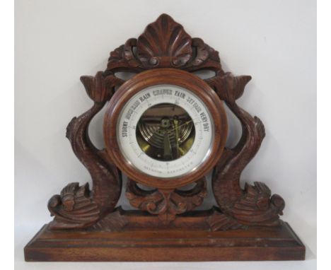 An aneroid barometer, the wooden case carved with mythical sea creatures, height 13ins