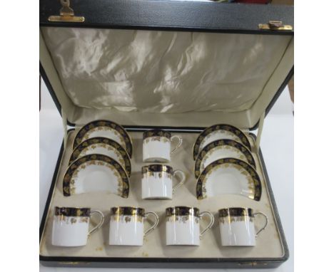 A cased Royal Worcester six piece coffee set, with band of blue and gilt vine