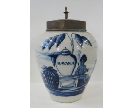 An 18th century Dutch faience pottery jar, decorated in blue and white with a Native American smoking a pipe next to a jar ti