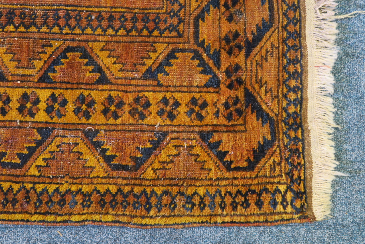 A Middle Eastern carpet with geometric designs on a gold and rust