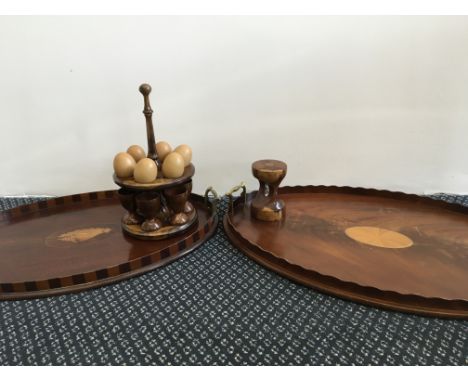 Two mahogany trays with inlay designs, together with a timer and an egg stand, with six cups and six eggs.