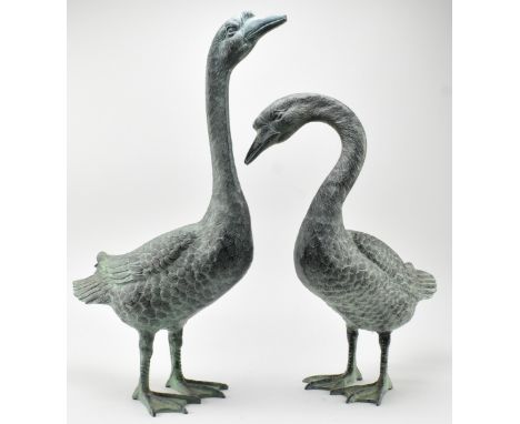 A pair of vintage bronzed zinc garden outdoor decorative sculptures of geese. The pair depicting each goose in different posi