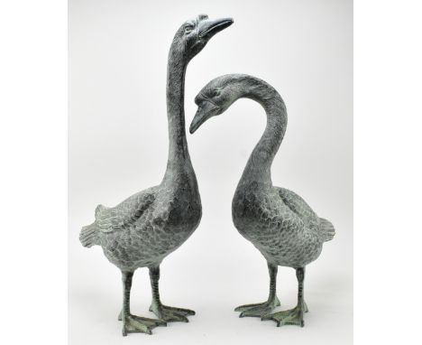 A pair of vintage bronzed zinc garden outdoor decorative sculptures of geese. The pair depicting each goose in different posi