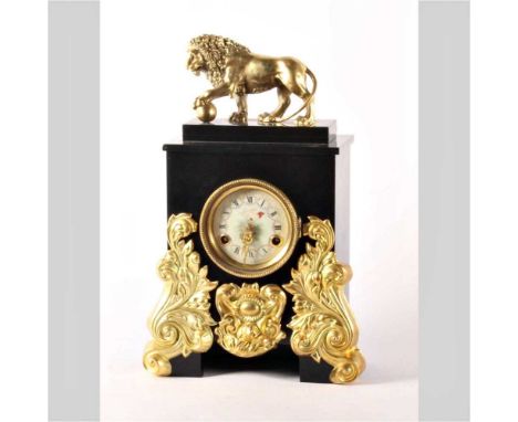 A black slate mantel clock, 19th century, surmounted by a gilt metal model of a lion, the enamel dial showing Roman numerals,
