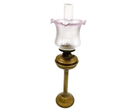 An early 20thC brass oil lamp, with a pink glass shade and reservoir, approx 58cm high overall. 