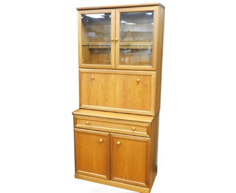 A teak side cabinet in the Nathan style, with two glazed doors including a shelf, and a fall front for cocktails, the base wi