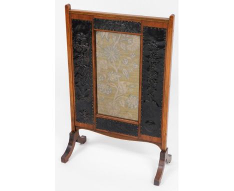 An Arts and Crafts walnut fire screen,  with applied metal panels of flowers, and centred embroidered tapestry, 91cm high, 57
