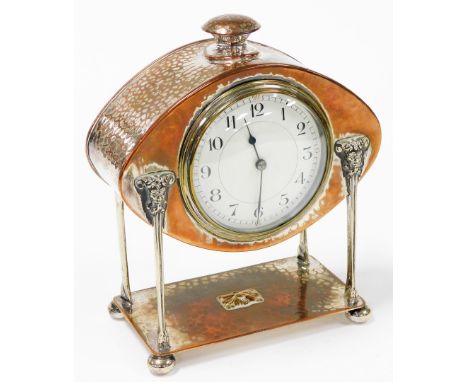 An Art &amp; Crafts electroplate on copper mantel clock by A E Jones, the hammered elliptical head enclosing a ceramic dial w