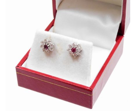 A pair of diamond and ruby set cluster earrings, the central ruby in a raised claw setting, surrounded by eight tiny diamonds