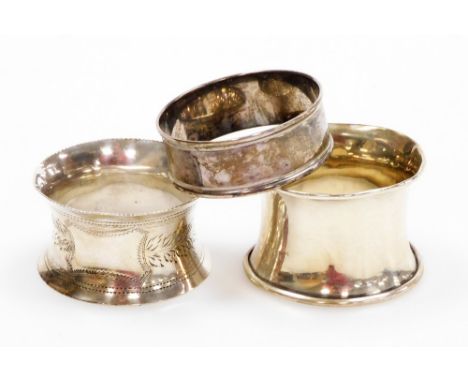 Three silver napkin rings, one of engine turned decoration, on flared rim with vacant cartouche, another of plain design with