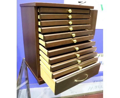 A modern locking coin cabinet with ten shallow trays above one deep drawer, each tray with lift-out sectional insert, one key