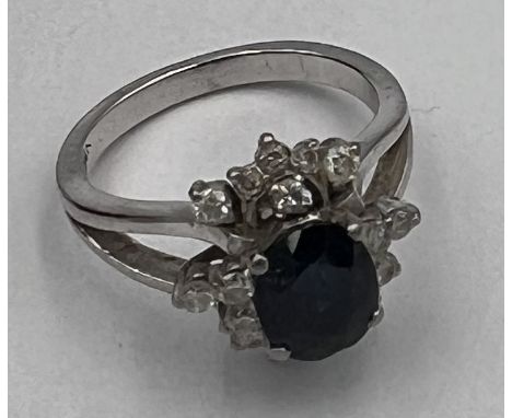 A 14 carat white gold ring set with central sapphire surrounded by diamonds. Size K. Weight 5gm. 