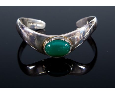 A sterling silver bangle, set with an oval green cabochon stone, London import marks 1991, total gross weight approx. 0.87ozt