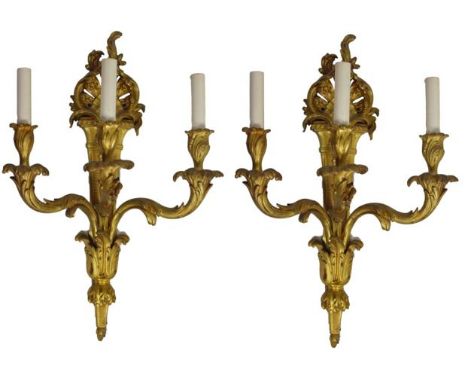 Late 19th to early 20th century, in Rococo style, this pair of three-light sconces is made of heavy bronze. Each backplate ha