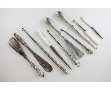 A pair of silver handled shoe horn and button hook tools, two other shoe horns, four button hooks, a letter opener and anothe