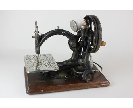 A Willcox & Gibbs sewing machine in wooden carry case with box of sewing tools