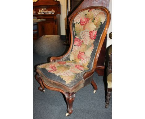 A Victorian  tapestry upholstered fireside chair with foliate carved mahogany frame, on cabriole legs and castors