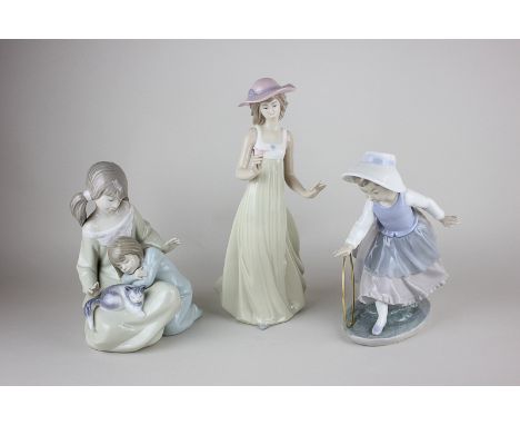 A Lladro porcelain figure group of two girls with a cat, together with a Nao porcelain figure of a girl in a hat holding a fl