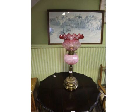 AN EARLY 20TH CENTURY BRASS BASED OIL LAMP with pink glass reservoir, and tinted crimple edged shade 