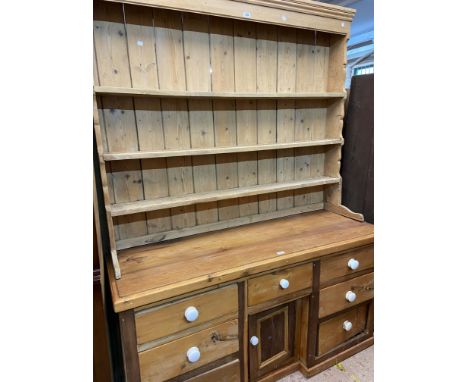 A 1.5m pine two part dresser with associated three shelf open plate rack over a Victorian base with central drawer and cupboa