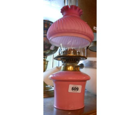 A Victorian twin burner oil lamp with opaque pink glass reservoir chimney and pink satin glass wrythen shade