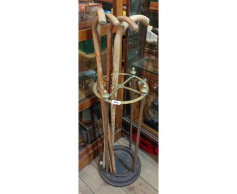 A cast iron and brass stick stand - sold with four wooden walking sticks