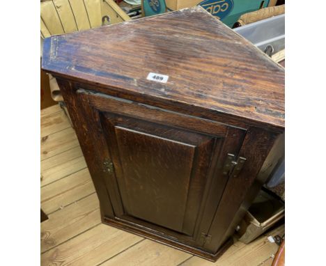 A 57cm antique oak wall hanging corner cabinet with canted sides and panelled door