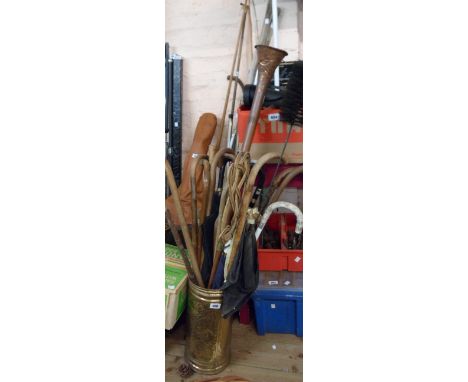 A pressed brass stick stand containing a large quantity of walking sticks, umbrellas, copper hunting horn, including silver c