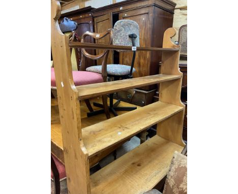 A 100cm old waxed pine four shelf open bookcase with shaped sides and partitioned recess under, set on plinth base