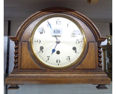 A vintage oak cased break dome top mantle clock with flanking barley twist decoration and eight day chiming movement
