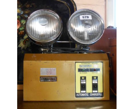 A vintage Starking brand emergency light with two large directional spotlights above a battery case