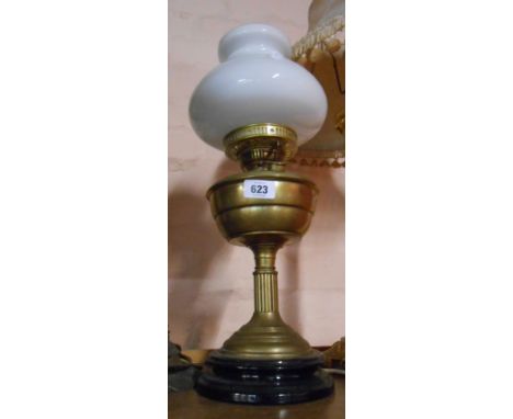 An old brass oil lamp with chimney and opaque glass shade